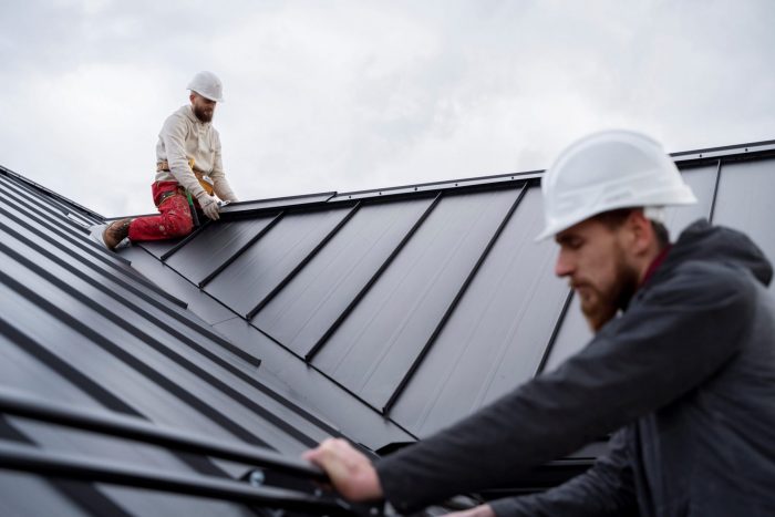 Men wearing safety hats on roof illustrate blog "The Importance of Regular Roof Inspections"