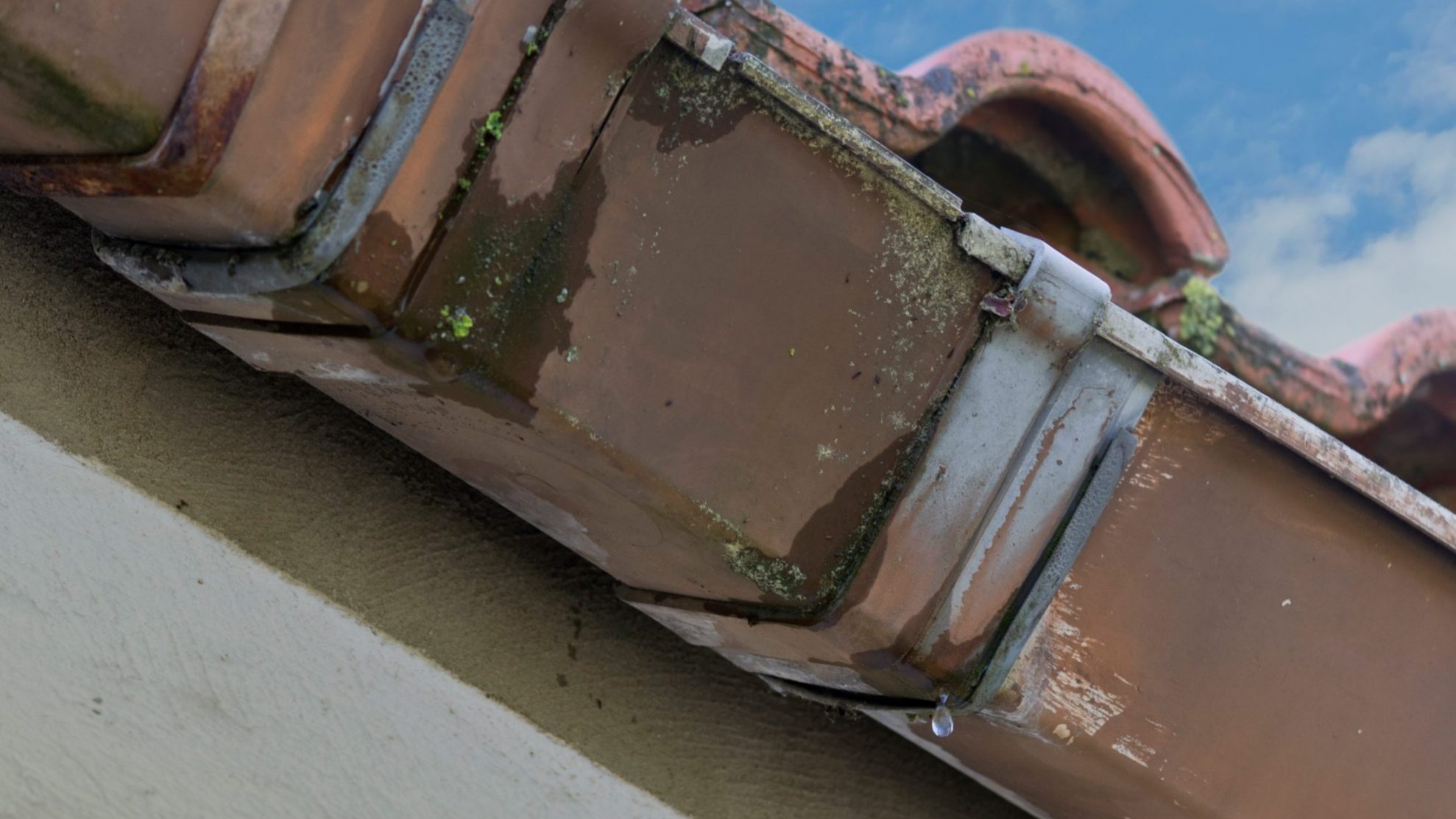 Closeup of gutter leaking water llustrates blog "Why Is My Roof Leaking?"