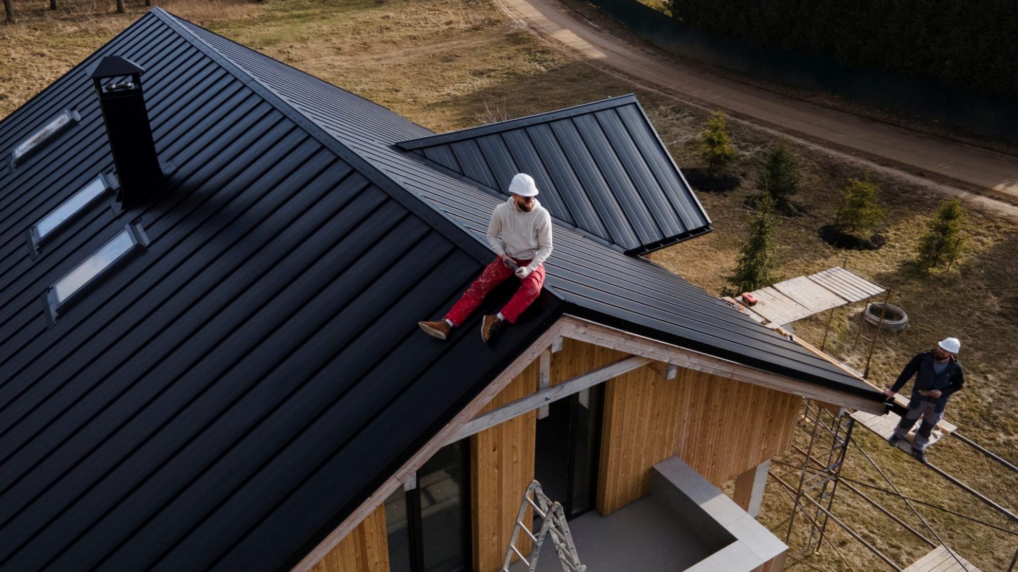 Long shot of roofing contractor sitting on roof illustrates blog "4 Hallmarks of a Great Roofing Contractor"