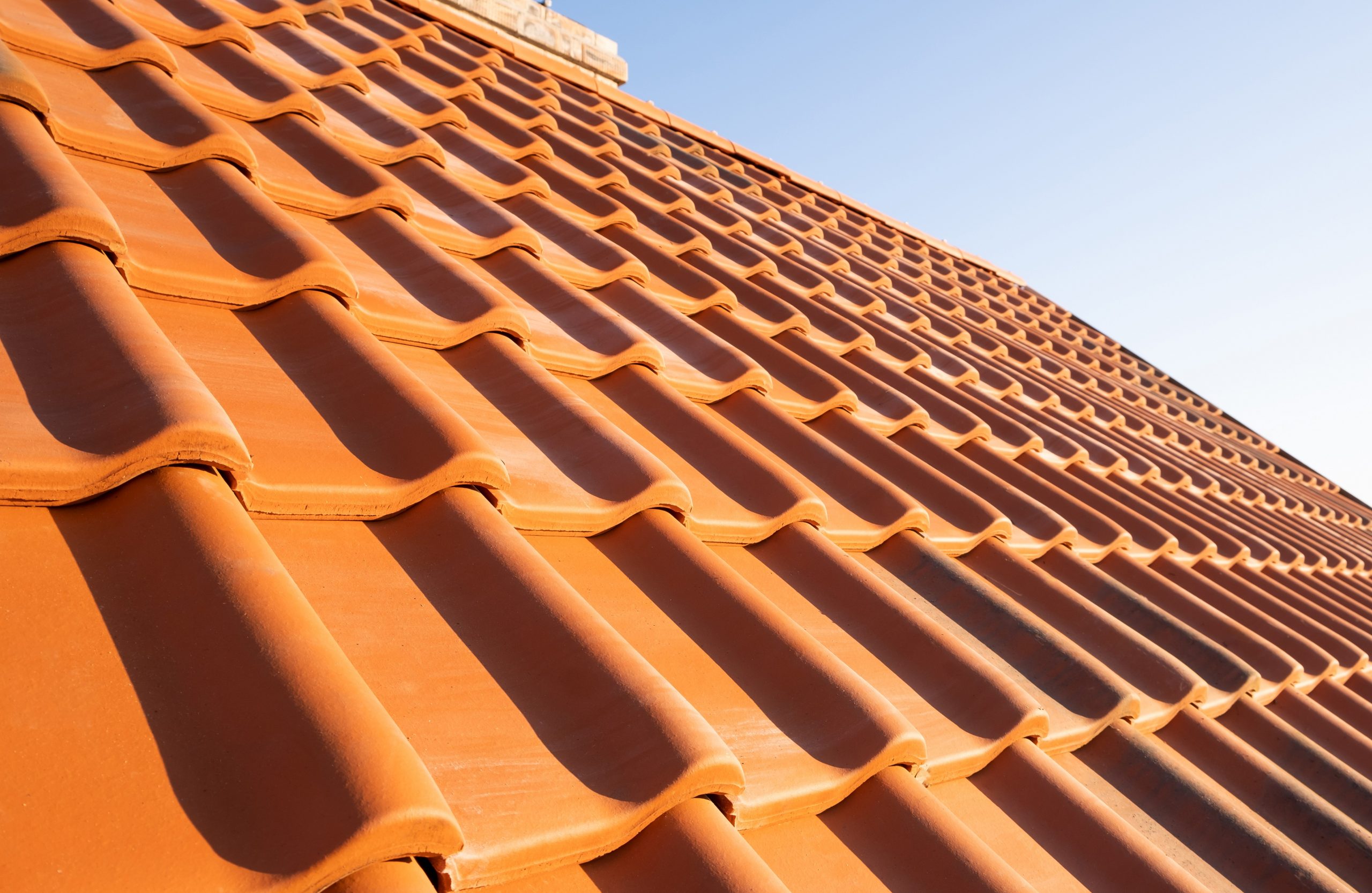 Overlapping rows of yellow ceramic roofing tiles covering reside Closeup of roof shingles illustrates blog "What Is Roofing Underlayment? "