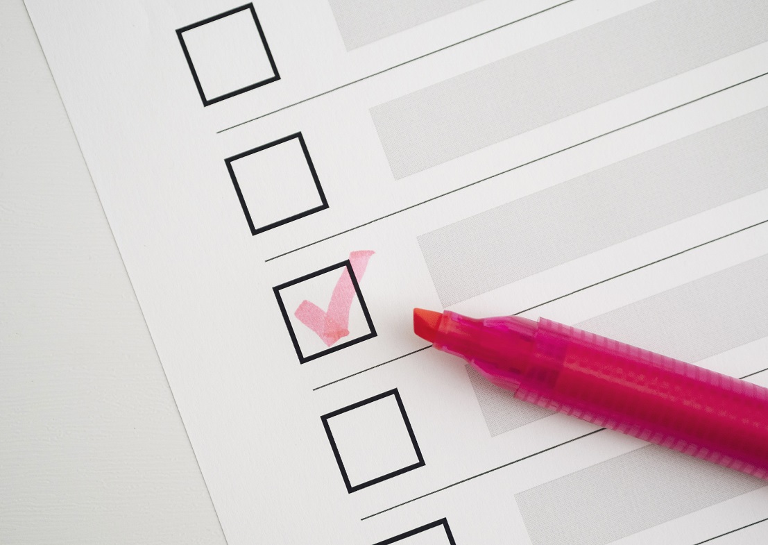 Closeup of checklist with checked box and pink marker illustrates blog "Your Roofing Maintenance Checklist"