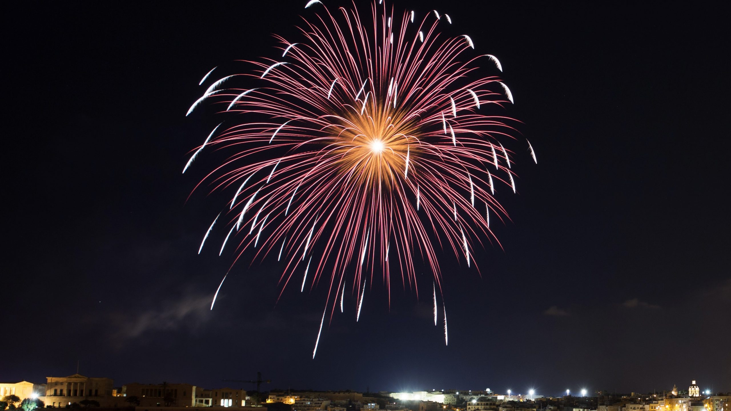 Fireworks display over roofs illustrate blog "Can Fireworks Damage Solar Panels?"